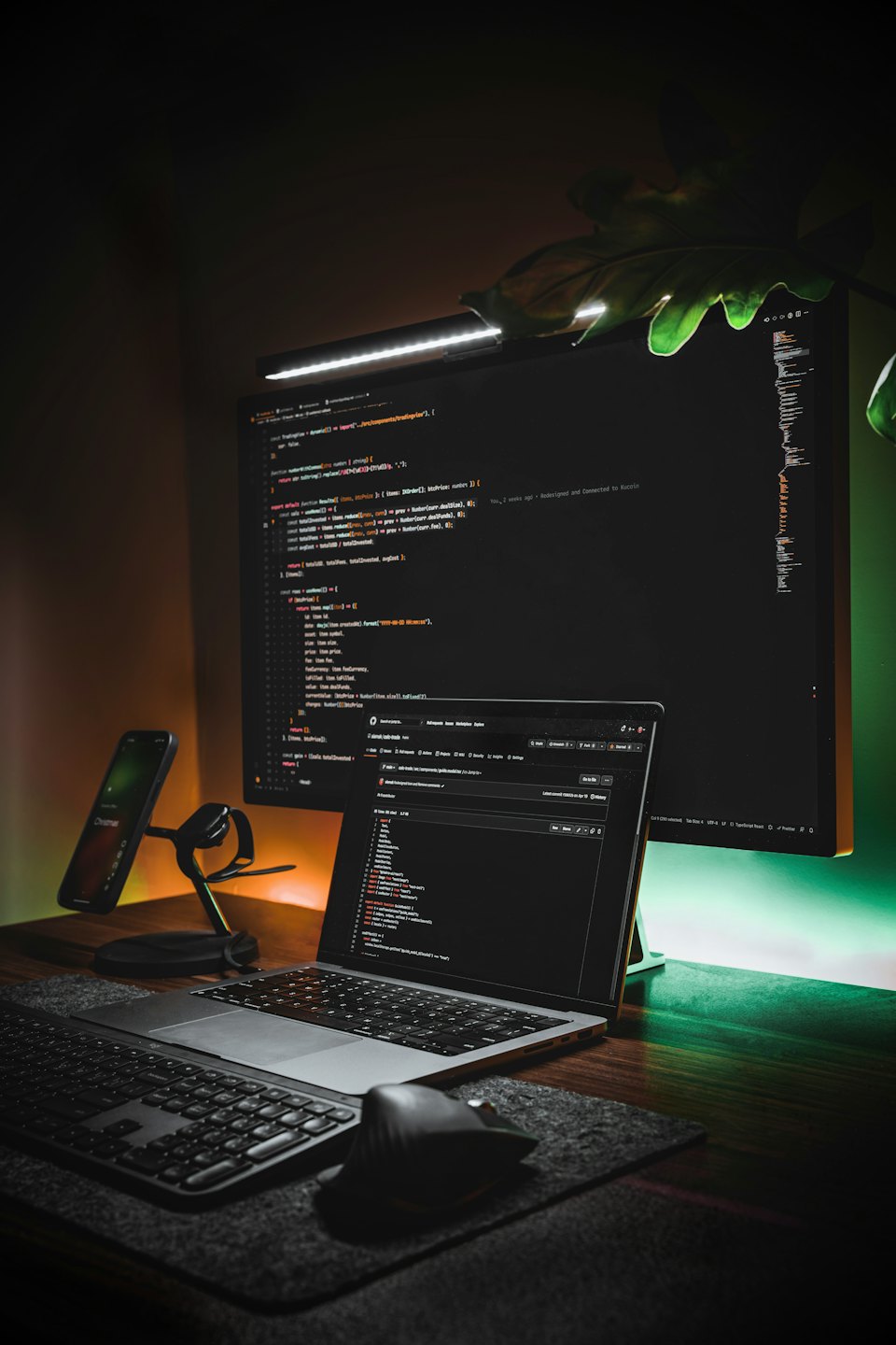 Monitor komputera i laptop wyświetlające kod na biurku.