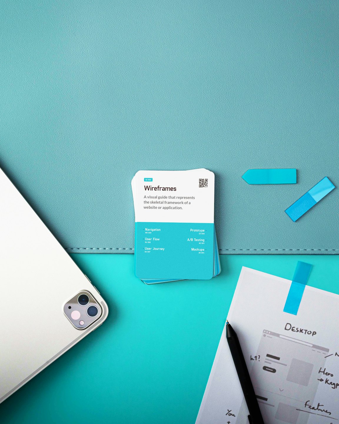 Tablet i karty do projektowania UX/UI na turkusowym tle.